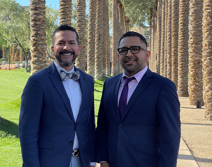 Naples prosthodontists Doctor Binns and Doctor Aquino smiling outdoors in suits