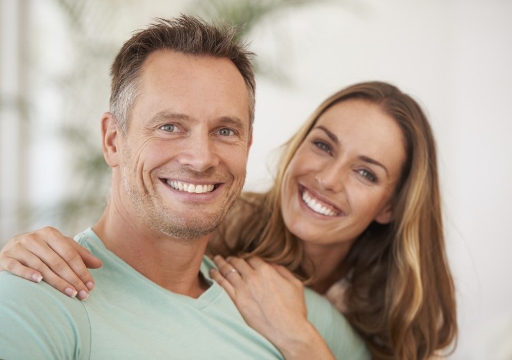 Man and woman smiling in their home after cosmetic dentistry in Naples