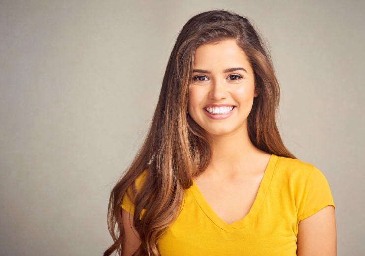 Young brunette woman smiling with dental bridges in Naples