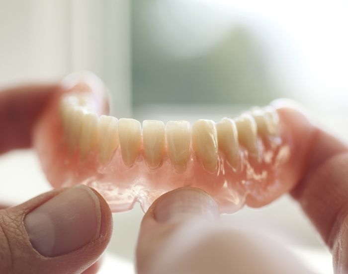 Two hands holding a denture