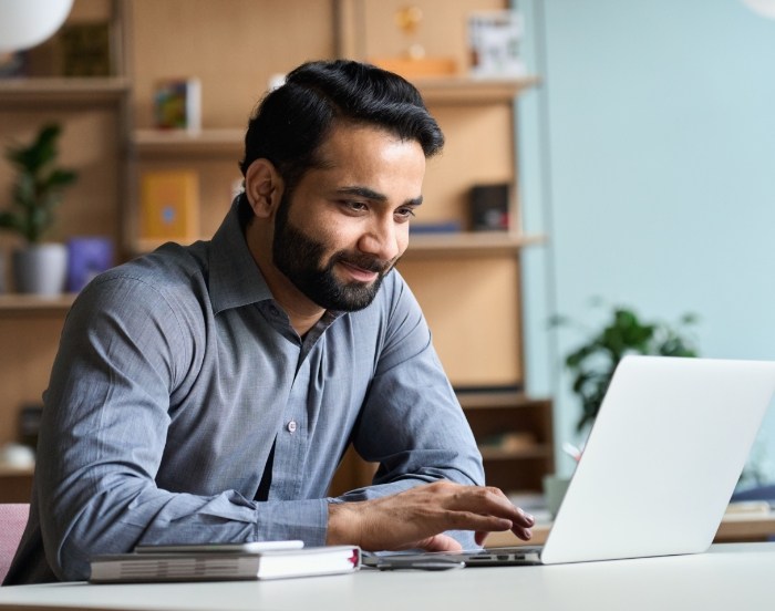 Man smiling while using laptop at desk