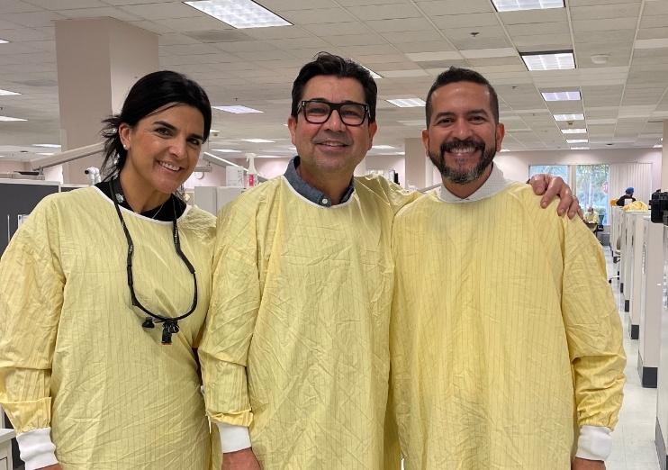 Three Naples dental team members wearing yellow scrub covers