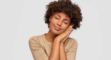 Woman making a pillow shape with her hands and pretending to sleep on it