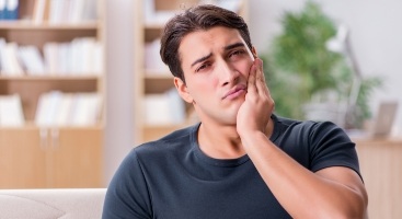 Man wincing in pain while touching the side of his face