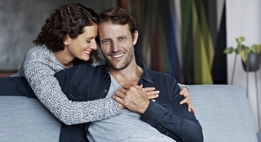 Woman hugging man while sitting on couch