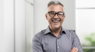 Smiling man with gray hair and gray collared shirt