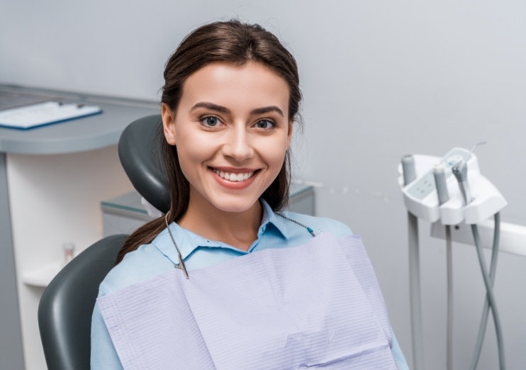 Brunette woman in dental chair smiling during preventive dentistry checkup