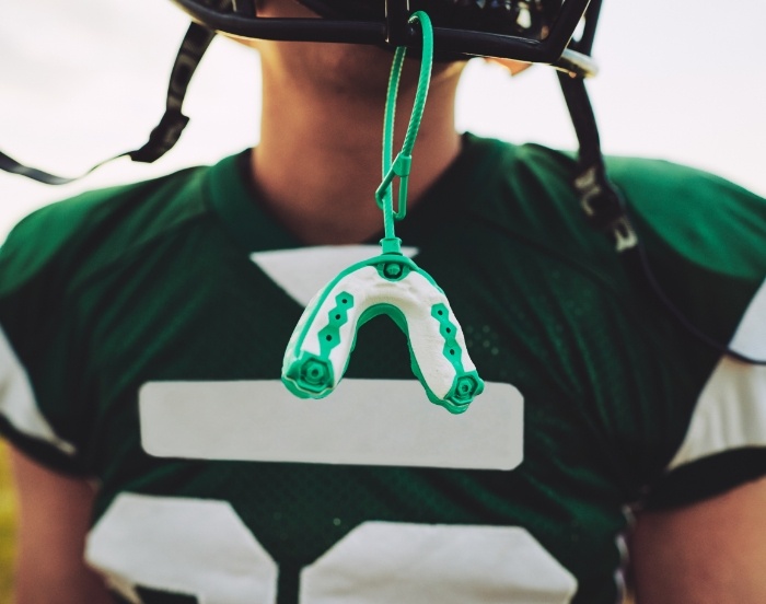 Football player with an athletic mouthguard dangling from a string on their helmet