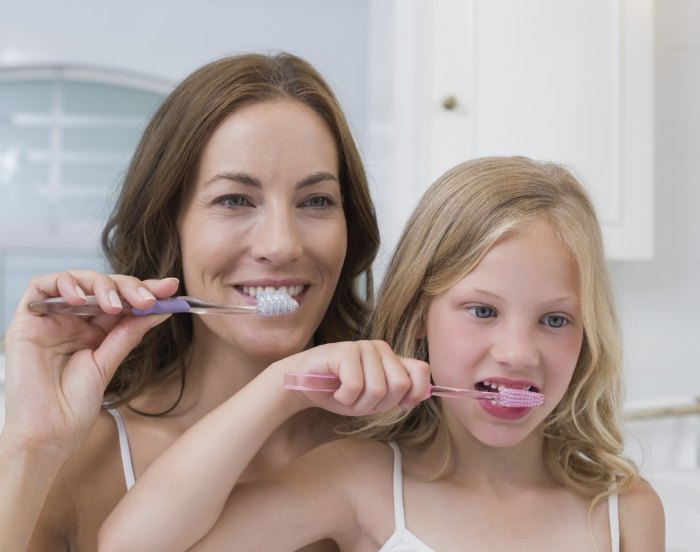 Mother and daughter brushing their teeth together