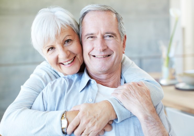 Senior couple smiling and hugging in their home