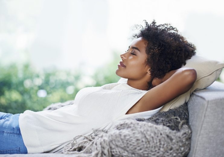 Woman relaxing on couch after sedation dentistry in Naples