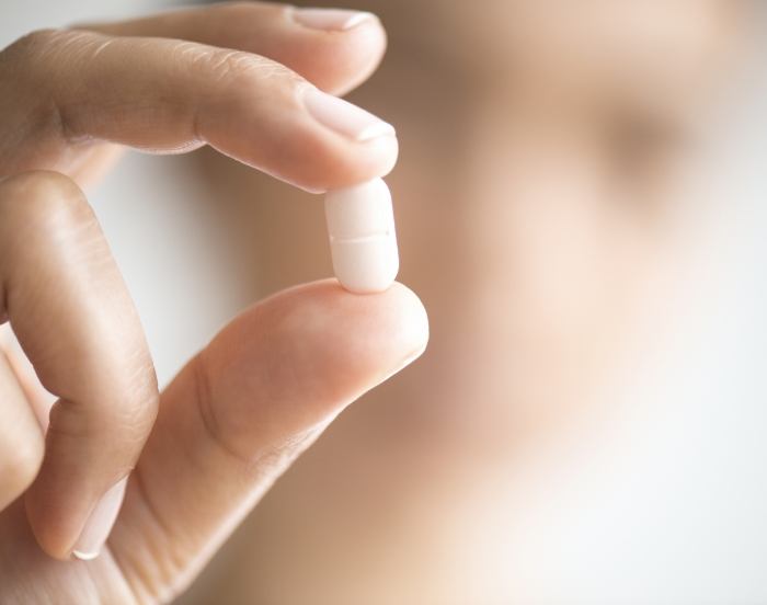 Close up of a hand holding a white pill