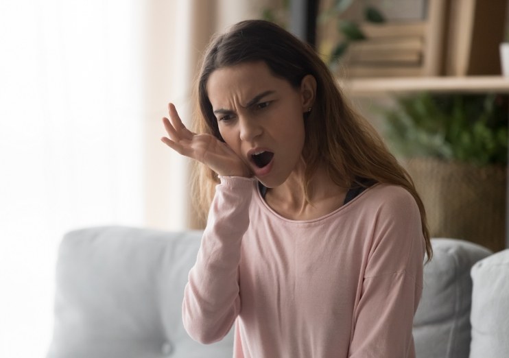 Woman holding the side of her jaw in pain before T M J treatment