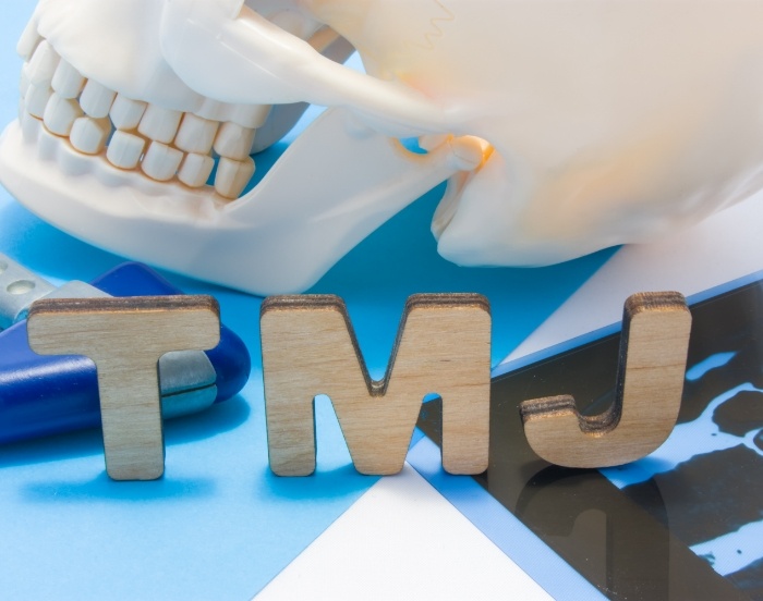 Model of skull on table next to wooden block letters T M J